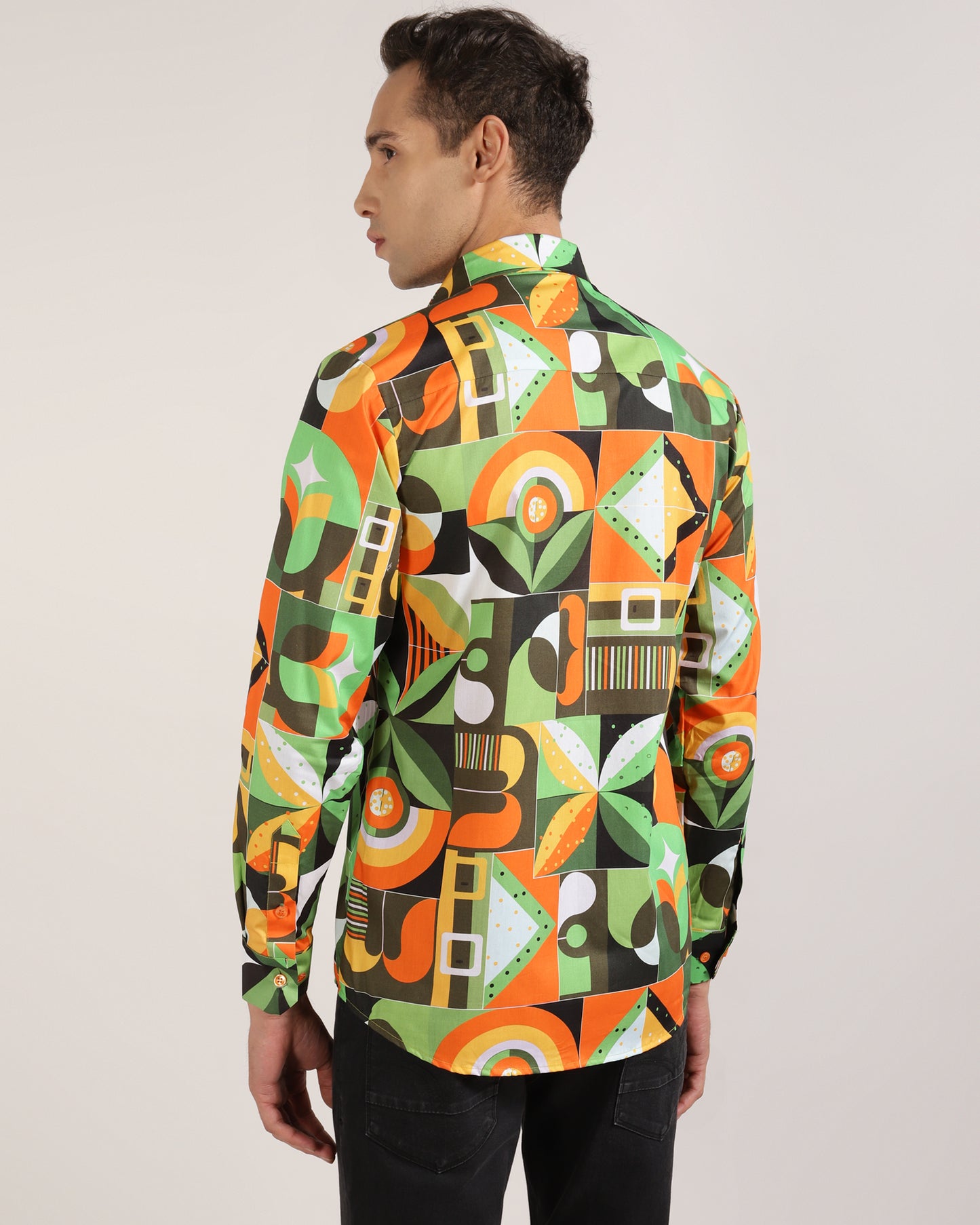 A man confidently wearing a green abstract geometric print shirt.