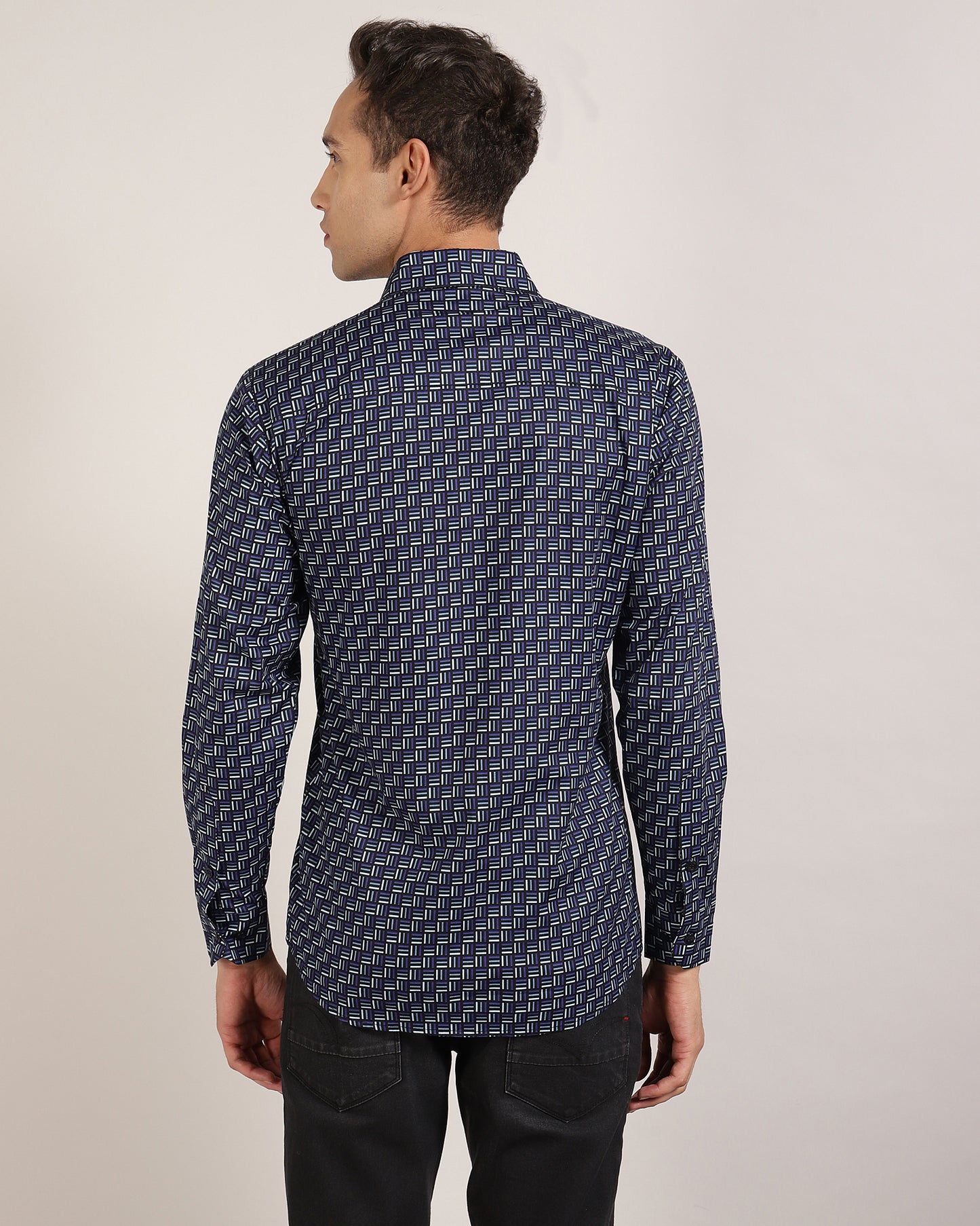 A blue geometric print shirt draped over a chair.